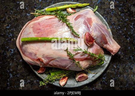 Traditional raw lamb shoulder meat ready to roast with Syrian seasoning, garlic, thyme and rosemary. Dark background. Stock Photo