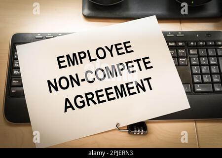 keyboard of an office computer with a piece of paper on top and a padlock, symbolizing the non compete agreement clauses Stock Photo