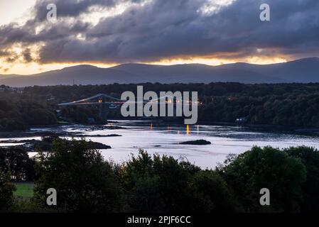 Menai Bridge, Anglesey, North Wales at dusk in mid October. A famous suspension bridge over the Menai Strait. Stock Photo