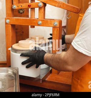 The cheesemaker puts cheese under press, whey. Home production ...
