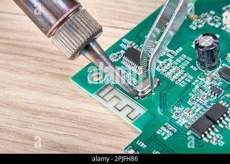 Installation, soldering a new part into a regular place on the electronic board using an electric soldering iron Stock Photo