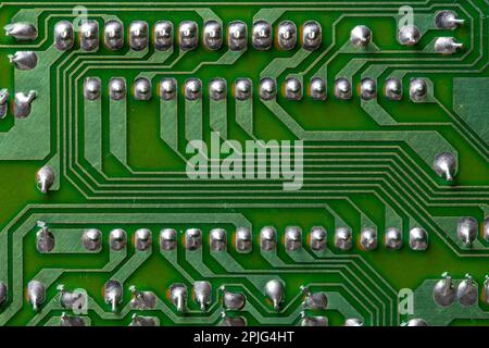 A part of a green printed circuit computer board with tracks. PCB without radio components. Old printed circuit board background with soldering trace, Stock Photo