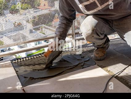 Bricklayer preparing cement on a slab using a notched trowel. I work in a construction. Concept of work, trade. Stock Photo