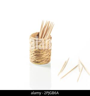 Cup made of straw for toothpicks with reflection in a white mirror background close-up Stock Photo