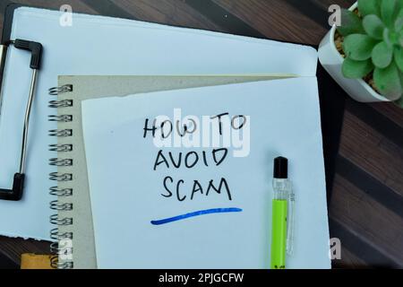 Concept of How to Avoid Scam write on sticky notes isolated on Wooden Table. Stock Photo