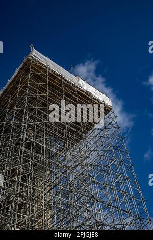 Scaffolding around a tall building against a blue sky Stock Photo