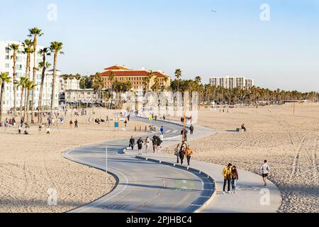 Santa Monica, California, USA - February 2022: People walking and riding cycles at sunset Stock Photo