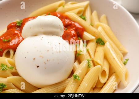 Delicious pasta with burrata cheese, sauce and herb in bowl, closeup Stock Photo