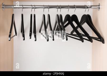 Set of black clothes hangers on wardrobe rail Stock Photo