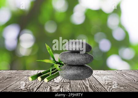 Stacked stones and bamboo stems on wooden table against blurred background. Zen concept Stock Photo