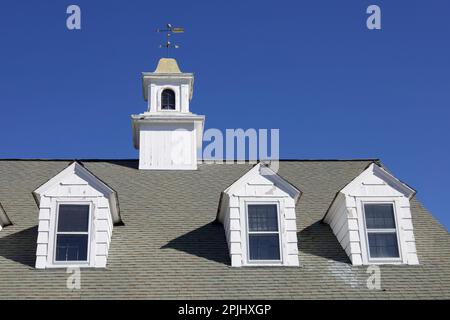 Top of building in East Haddam, Connecticut, USA with white dormer windows, roof, and tower with weathervane Stock Photo