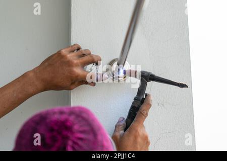 Male welds with argon-arc welding the clothesline in building house. Stock Photo