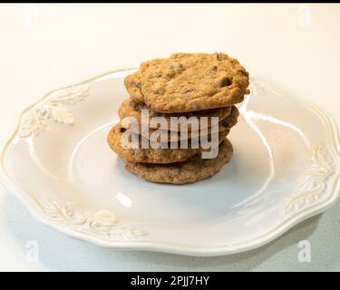A stack of 5 homemade chocolate chip cookies or biscuits on a white plate. Stock Photo