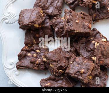 Homemade peanut chocolate fudge squares on a white plate, white background. USA. Stock Photo