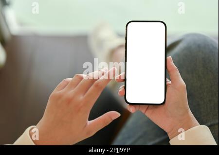 Smartphone white screen mockup in a woman's hand over blurred background. close-up top view image Stock Photo