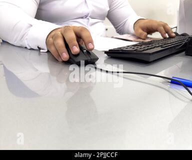Hands of businessman holding computer mouse and keyboard in office. Male office worker focused on a computer work. Hand on computer mouse close up Stock Photo