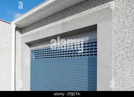 Roller shutter gate. Metal roller garage door as background. Automatic electric roll-up garage gate. Garage with blue rolling gates. Stock Photo