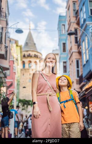 Portrait of beautiful mother and son tourists with view of Galata tower in Beyoglu, Istanbul, Turkey. Turkiye. Traveling with kids concept Stock Photo