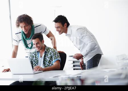 Check out this funny e-mail. Three male coworkers working in the office together. Stock Photo