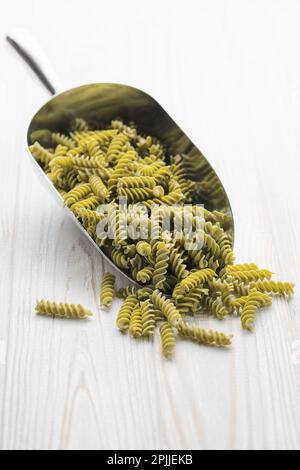 Mung bean fusilli pasta on a wooden background. Scoop with raw pasta and green mung bean. Gluten free pasta. Stock Photo