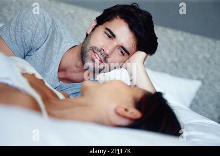 Bonding in the relaxation of their bed. a smiling couple lying in bed and talking. Stock Photo