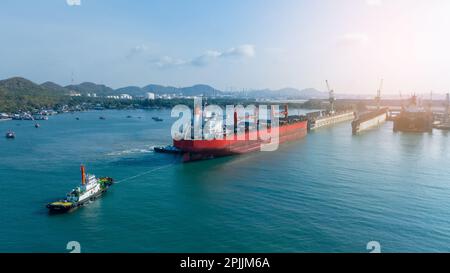 Tug boat Draging cargo container ship to dry dock concept maintenance service working in the sea. Insurance and Maintenance Cargo Ship concept. Freigh Stock Photo