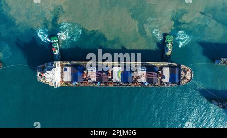 Tug boat Draging cargo container ship to dry dock concept maintenance service working in the sea. Insurance and Maintenance Cargo Ship concept. Freigh Stock Photo