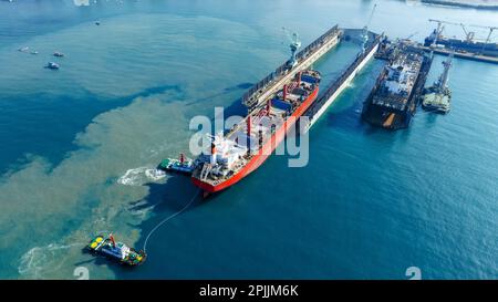 Tug boat Draging cargo container ship to dry dock concept maintenance service working in the sea. Insurance and Maintenance Cargo Ship concept. Freigh Stock Photo