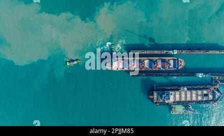 Tug boat Draging cargo container ship to dry dock concept maintenance service working in the sea. Insurance and Maintenance Cargo Ship concept. Freigh Stock Photo