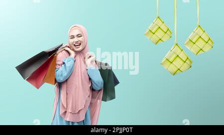 Asian Muslim woman in veil holding shopping bags with colored background Stock Photo