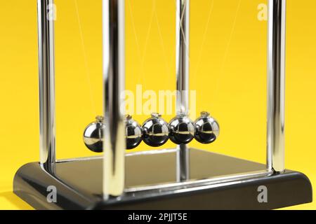 Newton's cradle on yellow background, closeup. Physics law of energy conservation Stock Photo