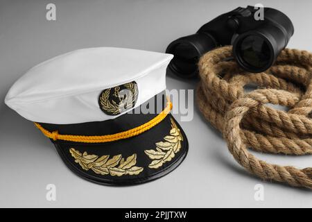 Peaked cap, rope and binoculars on light grey background Stock Photo