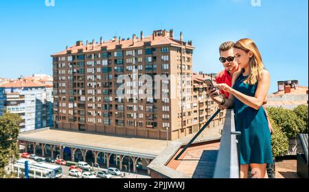 Young couple looking mobile in rooftop on a summer day Stock Photo