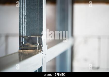 Close-up of a metal profile frame for a wall. Room divider under construction. Connection using self-tapping screws with a drill. Stiffening ribs in a Stock Photo