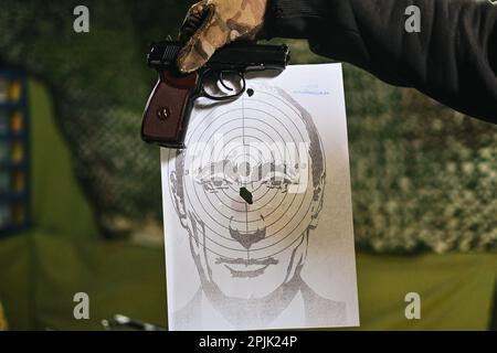 April 2, 2023, Lviv, Lviv region, Ukraine: Andriy, the owner of the shooting range, holds a target with Putin's face with a hit right in the middle and a dummy gun above it. An improvised shooting range managed by Andriy, a young Ukrainian, in a street near Rynok Square, in Lviv, western Ukraine, in which people can come and shoot with airsoft weapons on targets made of a picture of Russian President Vladimir Putin's face. (Credit Image: © Adrien Fillon/ZUMA Press Wire) EDITORIAL USAGE ONLY! Not for Commercial USAGE! Stock Photo