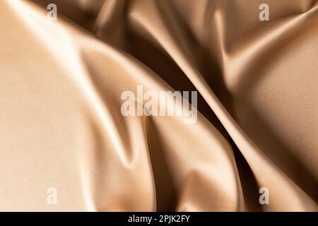 Close up of plain beige satin fabric with folds, copy space Stock Photo