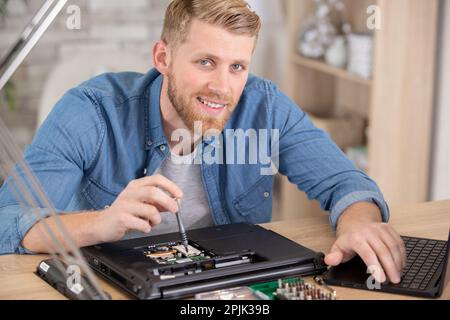 young energetic male tech or engineer repairs laptop Stock Photo