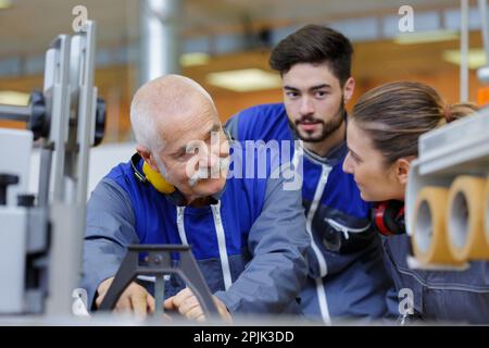 engineer and apprentice working on machine in factory Stock Photo