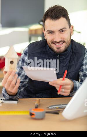 carpenter making the birdhouse smiling Stock Photo