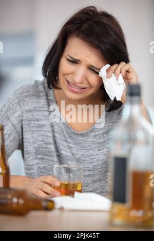 young depressed woman sinking in alcohol Stock Photo