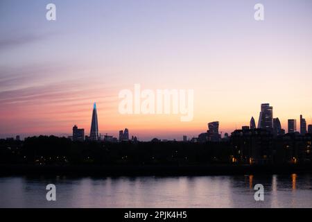 Pink, purple and orange striped radiatus altostratus clouds cover the sky over the London skyline at sunset. Stock Photo