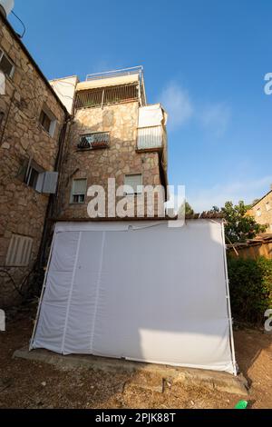 Sukkah covered with white cloth, built in the yard of a building in Jerusalem. The Jewish holiday of Sukkot Stock Photo