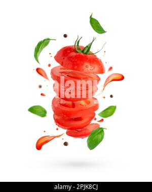 Flying sliced tomato with flowing splashes and basil leaves on white background with clipping path. Stock Photo