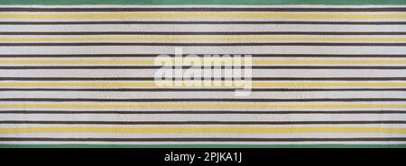 White roughcast wall with painted yellow and brown stripes and green border Stock Photo