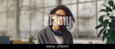 Young woman student in headphones making notes in a notebook in the modern coworking Stock Photo