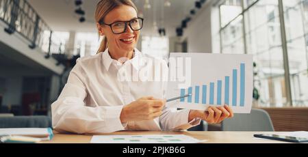 Smiling woman accountant have online briefing with colleagues while sitting on office desk Stock Photo