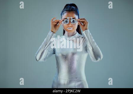 Model dressed as a silver robot Holding prosthesis looking at camera on grey background Stock Photo