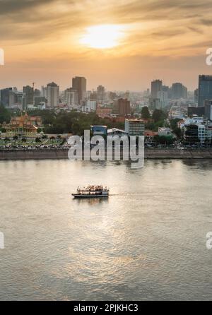 Rooftop view,looking across to the Riverside area of Cambodia's capital city.Sunset over Royal Palace and high rise buildings as a small boat drifts b Stock Photo