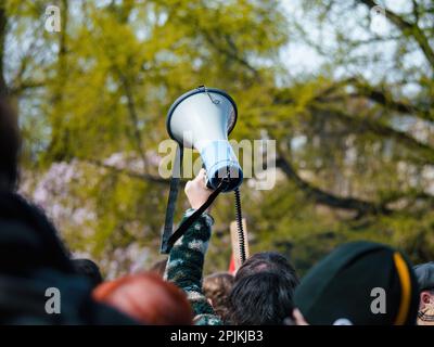 A large crowd of protesters hold up signs and banners, shouting their message of resistance against a political crisis. Their raised arms signal the start of an activist movement for freedom. Stock Photo