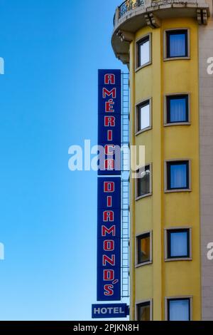 Lisbon, Portugal - January 4, 2023: America Diamond's Hotel. A yellow tower on the right side of the image with many windows and a banner, and the bac Stock Photo